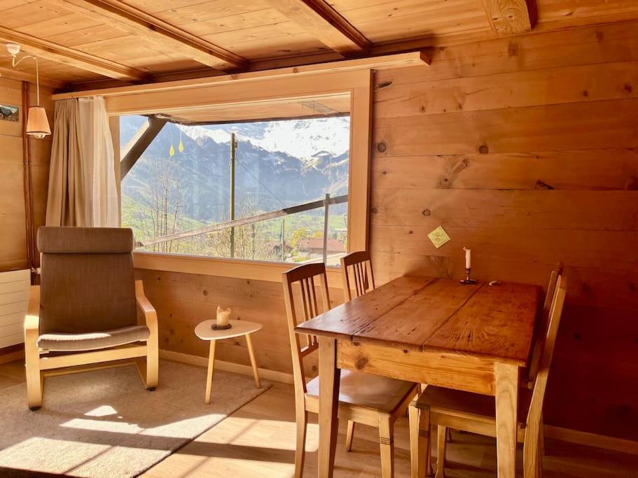 una sala da pranzo con tavolo, sedie e finestra di Chalet Sonnenheim, Wohnung mit Panoramafenster ad Adelboden