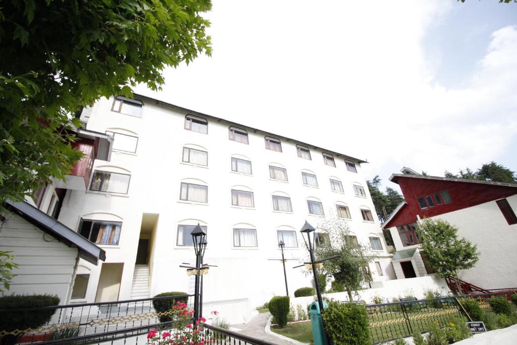 Ein weißes Gebäude mit einem Zaun davor. in der Unterkunft Vardaan Hotels - PatniTop in Patnitop