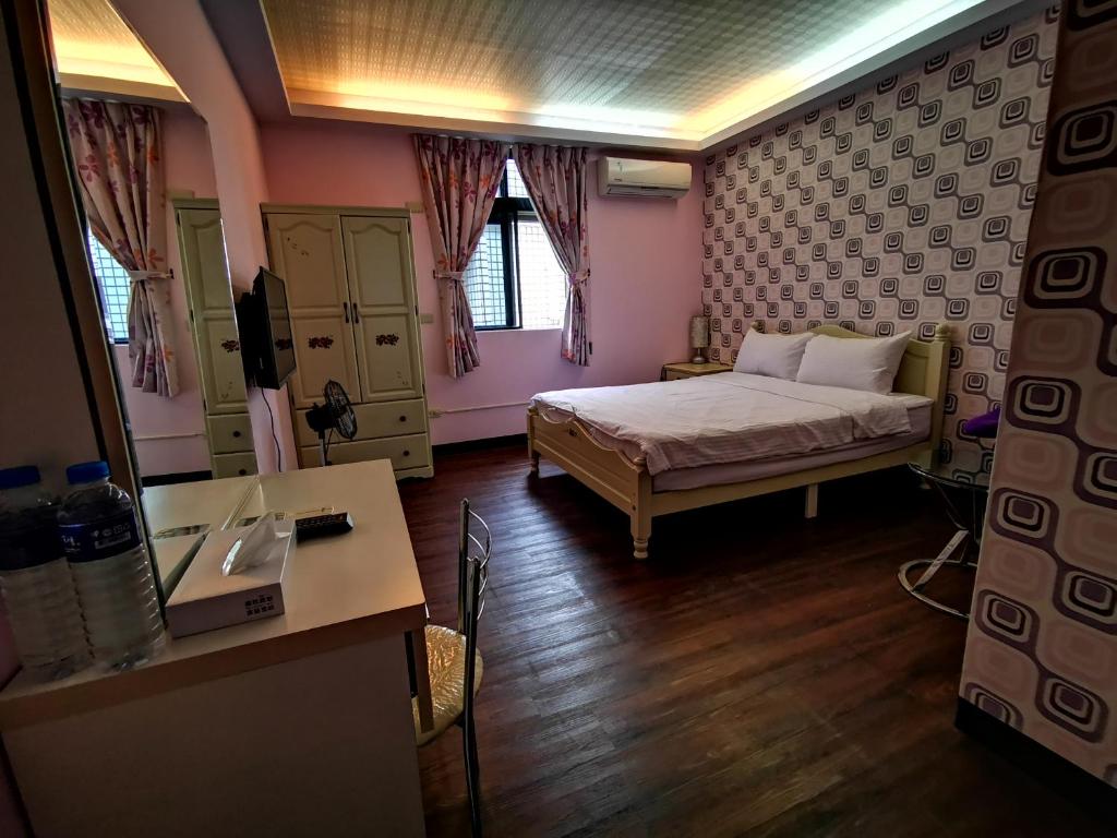 a bedroom with a bed and a desk in a room at Tai Yu Ju Bao Fang B&B in Yongan