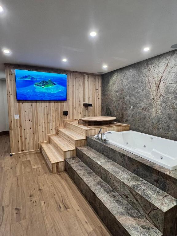a bathroom with a tub and a tv on the wall at Romantic Luxury Retreat with Private Sauna & Spa, Pet Friendly, Elkside Hideout B&B in Canmore