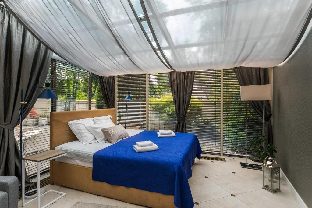 a bedroom with a bed with blue sheets and a window at A11 Apartments & SPA Dermique in Kraków