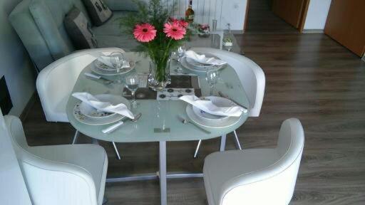 une table blanche avec un vase de fleurs et de chaises dans l'établissement Apartments Sava, à Zagreb