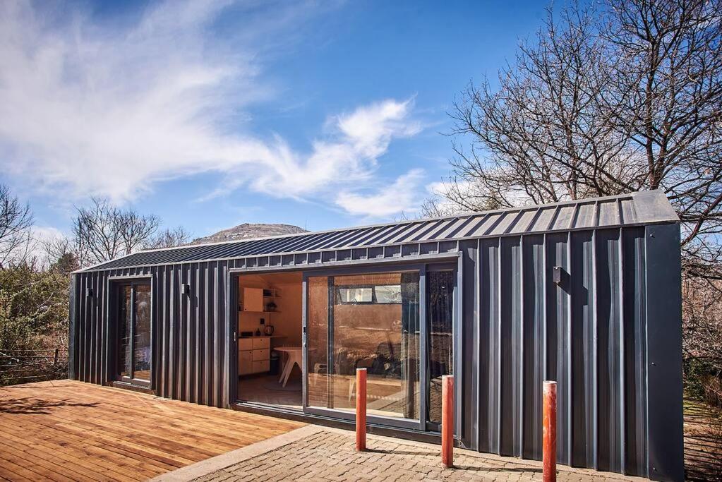 une petite maison noire avec des portes en verre sur une terrasse dans l'établissement Clarens 'Gazza' Pod, à Clarens