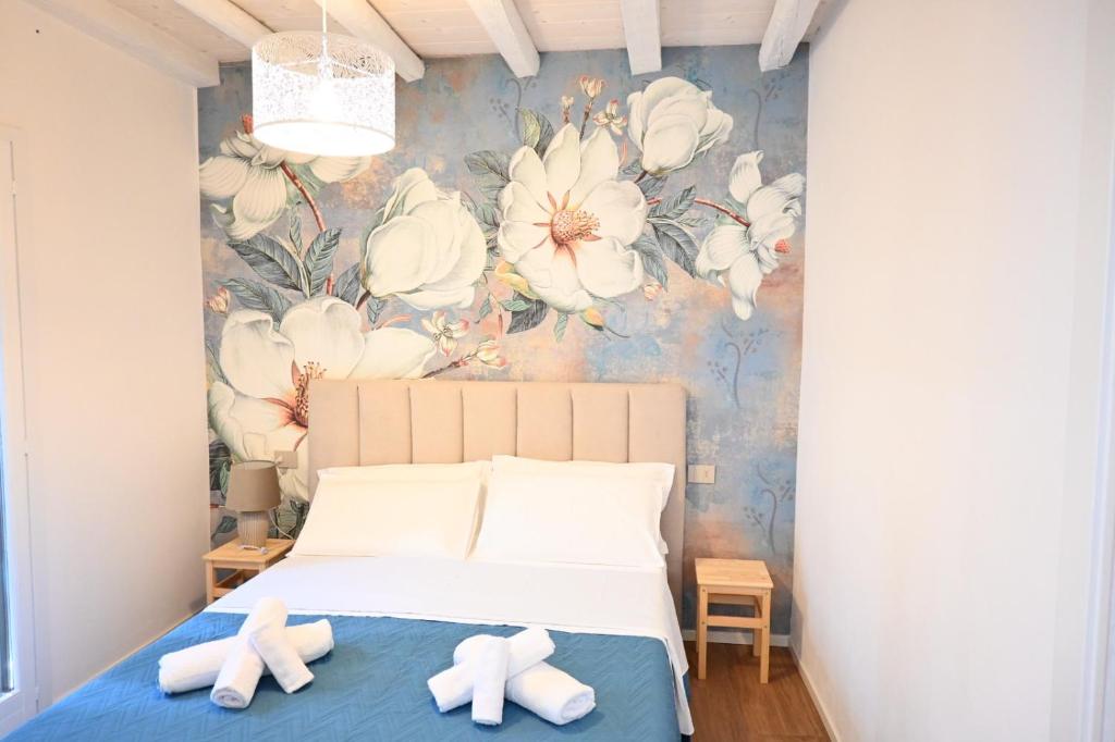 una camera da letto con un letto con fiori bianchi sul muro di Garofoli Apartments a San Giovanni Lupatoto