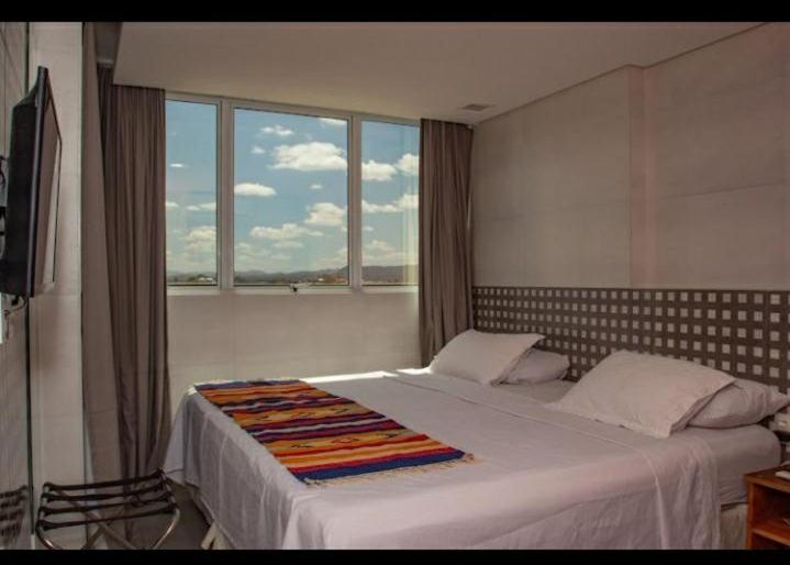 a bedroom with a large bed with a large window at EMA HOTEL in Serra Talhada