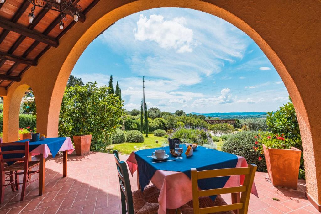 an arched patio with tables and chairs and a view at Borgo De Salaioli in Scansano