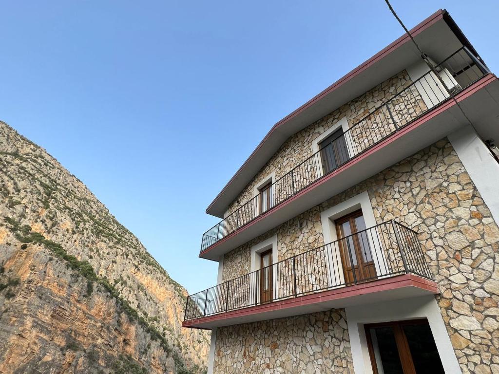 un edificio con balcones junto a una pared de piedra en L'oasi del raganello en Civita