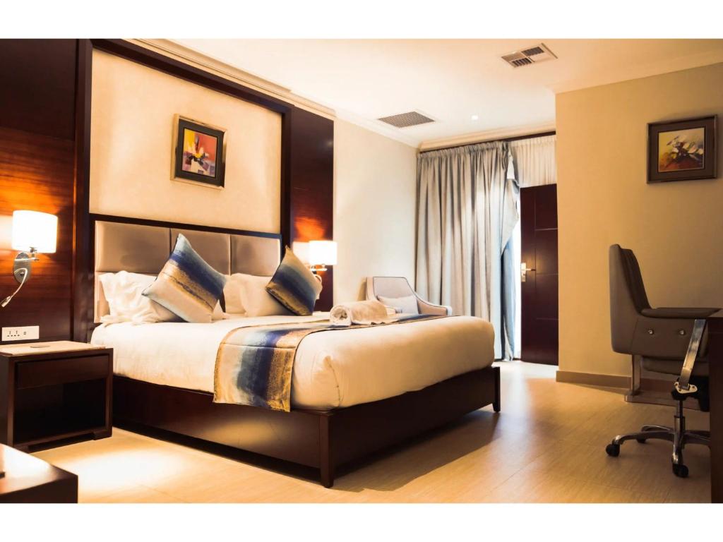a bedroom with a bed and a desk and a chair at Grand Palace Hotel Lusaka in Lusaka