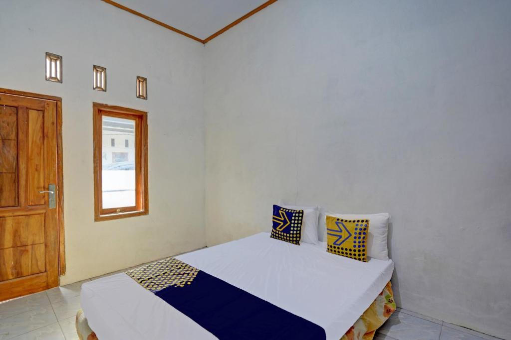 a bedroom with a bed and a window and a door at SPOT ON 92906 Surya Indah Homestay Syariah in Mojokerto