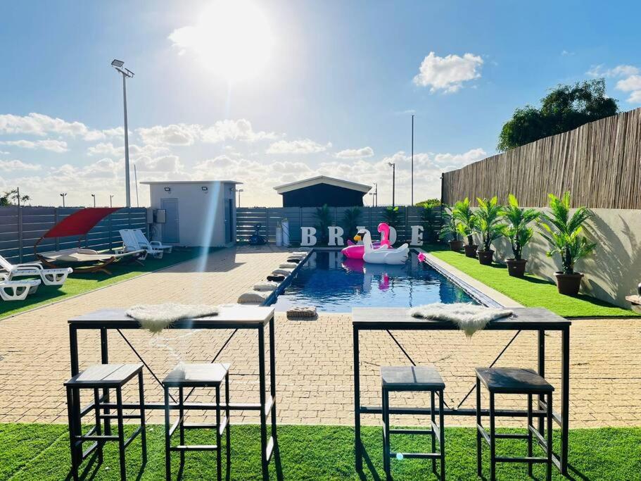 a table and chairs in front of a swimming pool at אחוזת נווה גד in Telamim