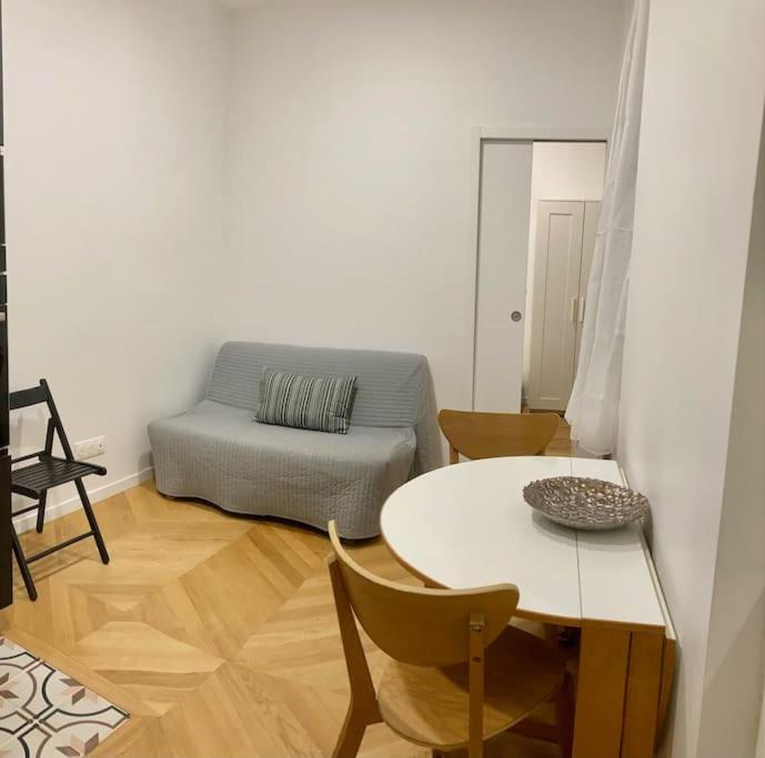 een woonkamer met een tafel en een bank bij Appartement confortable et complet in Clichy