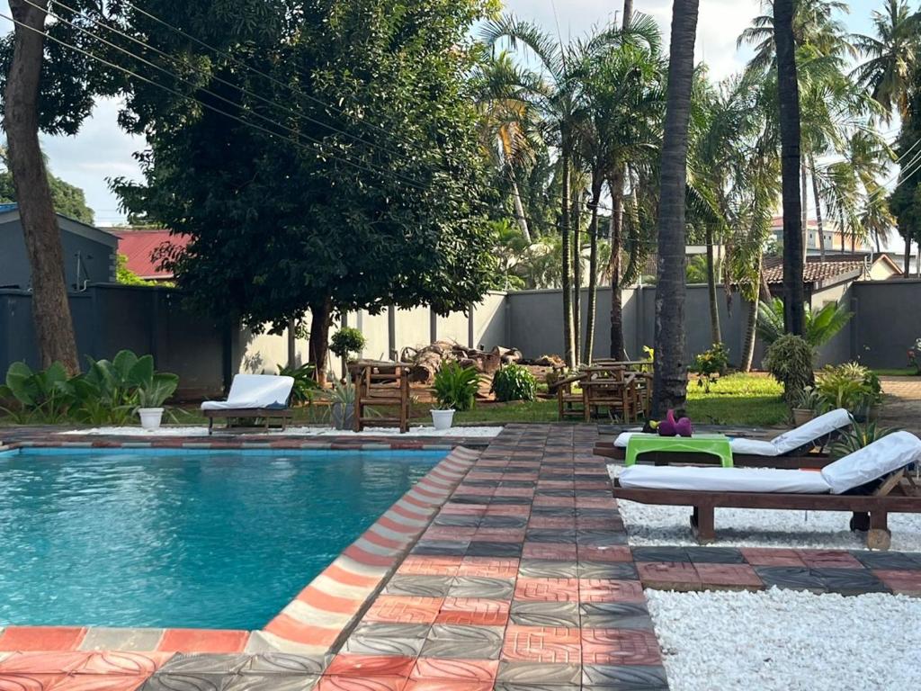 a swimming pool with chaise lounges and chairs in a resort at BBQ Lounge in Dar es Salaam