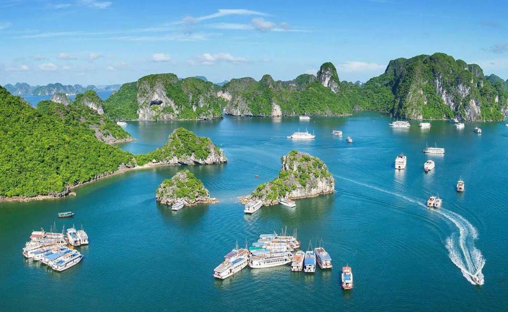 a group of boats in a bay with limestone islands at PHÚC AN HOSTEL in Cat Ba