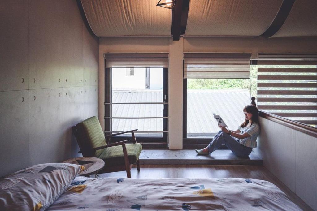 a woman sitting in a window reading a magazine at Taipei Jinguashi Cloud Mountain Homestay B&amp;B in Jiufen