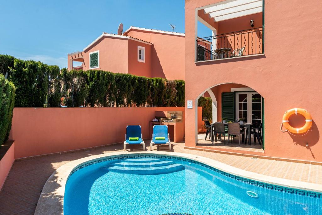 uma villa com piscina em frente a uma casa em Villas Cala Galdana em Cala Galdana