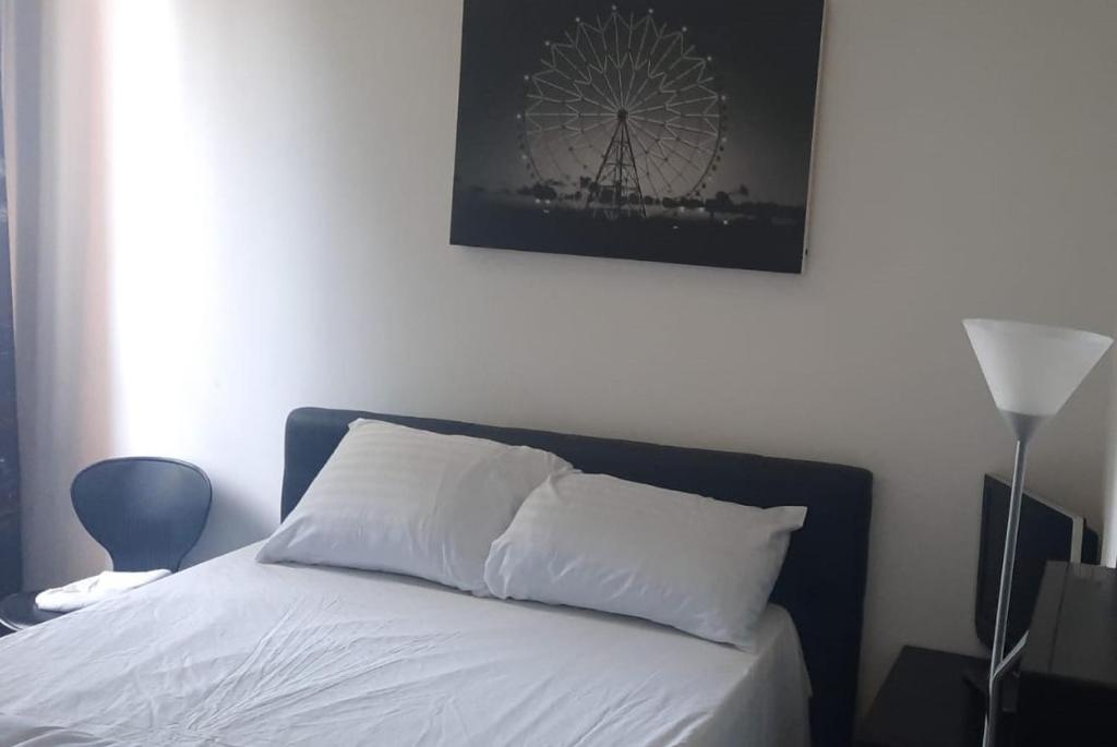 un lit avec des draps blancs et une photo d'une roue ferris dans l'établissement JUST ROOMS, à Sarcelles