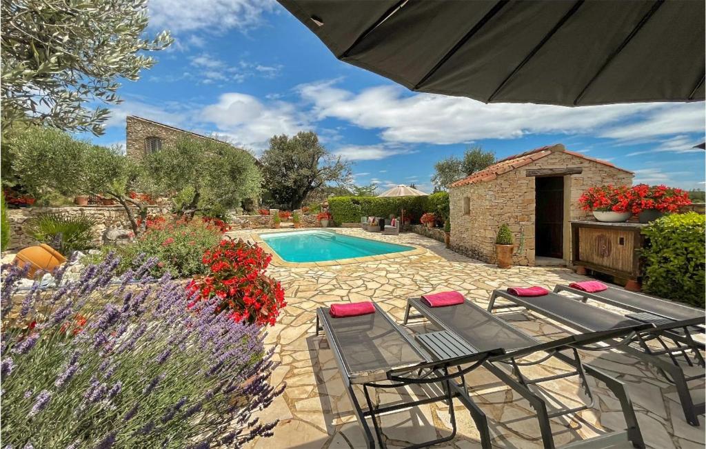a swimming pool in a garden with chairs and an umbrella at Awesome Home In Fontarches With 2 Bedrooms, Wifi And Outdoor Swimming Pool in Fontarèches