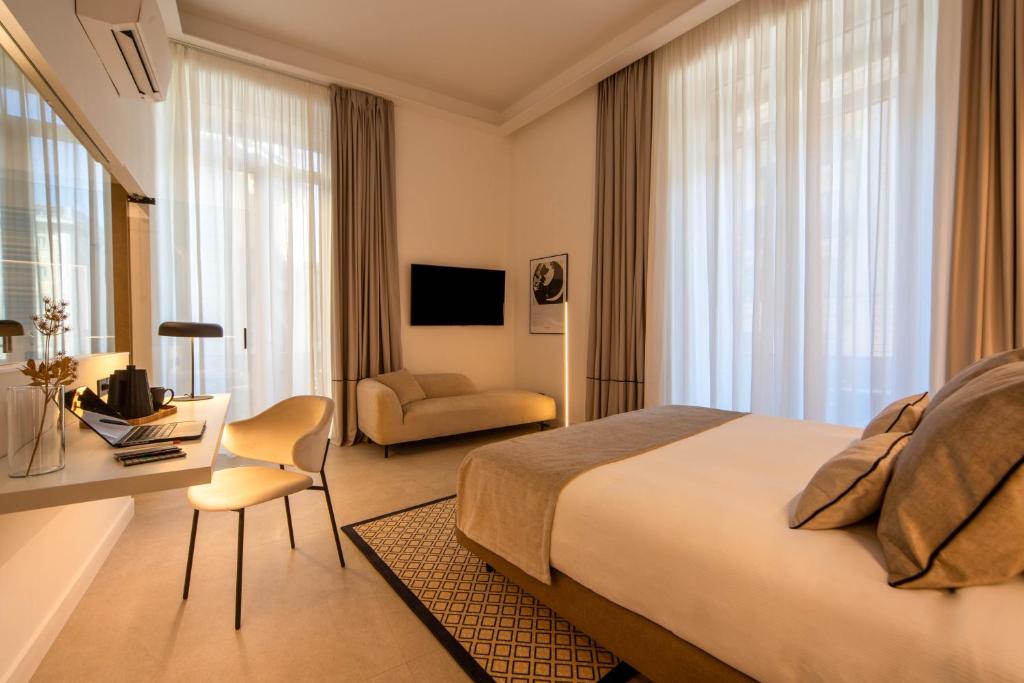 ein Hotelzimmer mit einem großen Bett und einem Schreibtisch in der Unterkunft MAMALU - Studios and Suites in Neapel