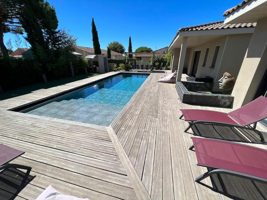 une piscine avec deux chaises à côté d'une maison dans l'établissement Splendide villa avec piscine et salle cinéma, au Grau-dʼAgde