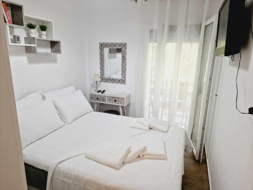 a white bedroom with a bed and a mirror at Valentina's Apartment in Olympiada