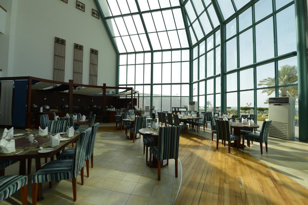a dining room with tables and chairs and windows at Mirfa Hotel in Al Mirfa