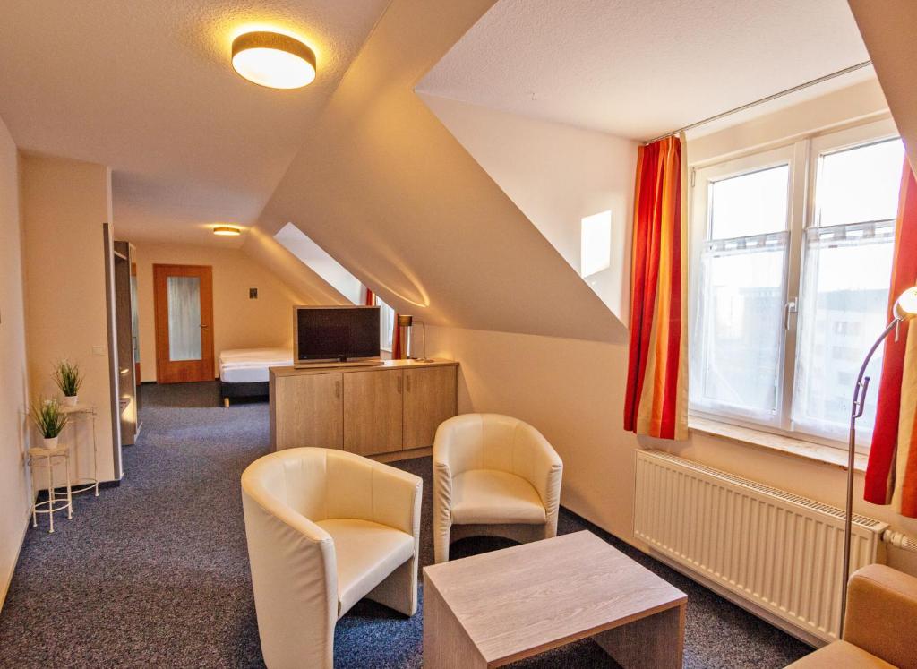 a room with chairs and a bed and a tv at Hotel Zur Sonne in Waren
