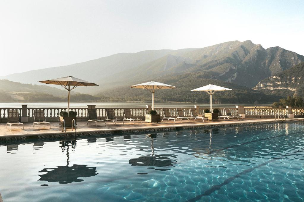 a swimming pool with umbrellas and chairs and a mountain at Hotel Terradets in Cellers