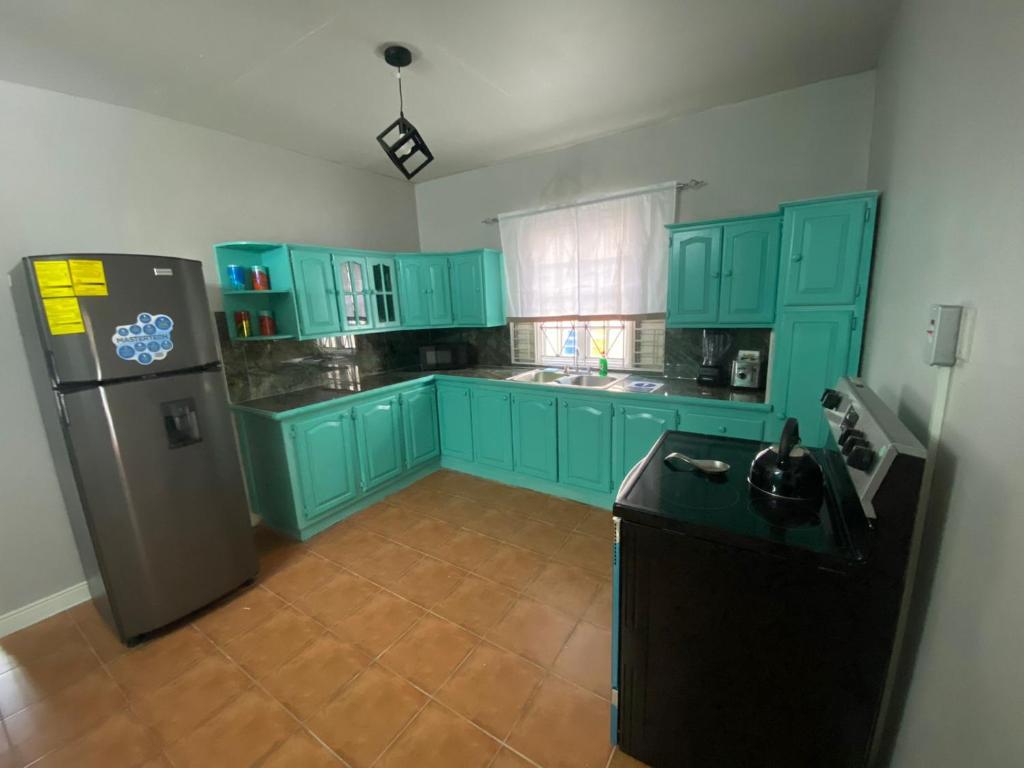 uma cozinha com armários azuis e um frigorífico preto em Cozy 2 bedroom Townhouse in gated community, KGN8 Newly installed solar hot water system em Kingston