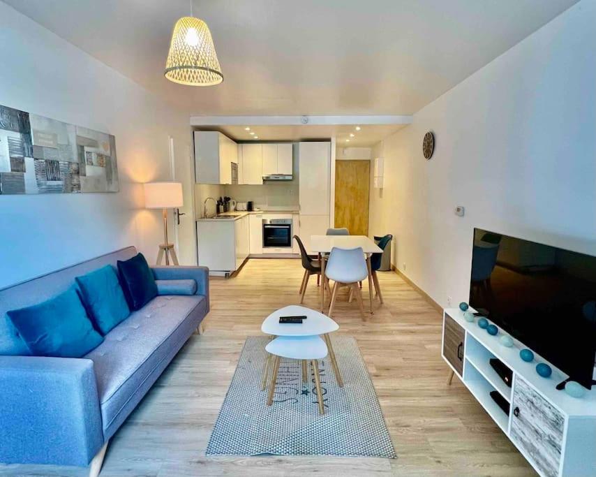 ein Wohnzimmer mit einem blauen Sofa und einem Tisch in der Unterkunft Le Genevois - Parking gratuit in Annemasse