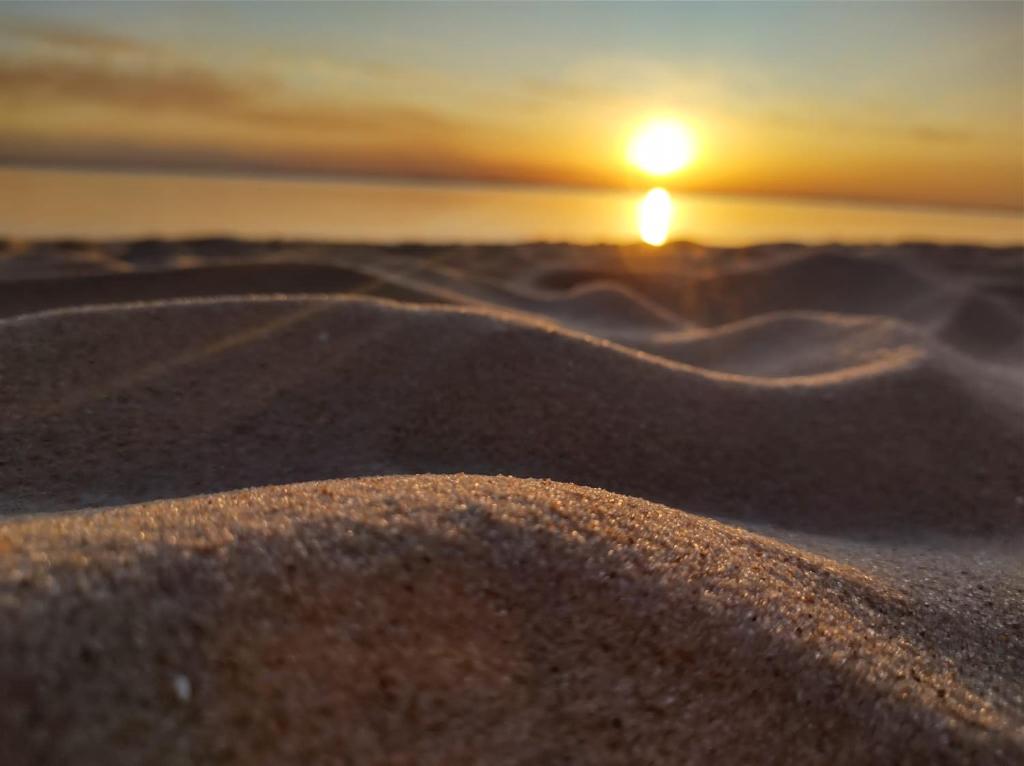 un coucher de soleil sur une dune de sable avec le soleil en arrière-plan dans l'établissement APART PELUSA, à Fray Bentos