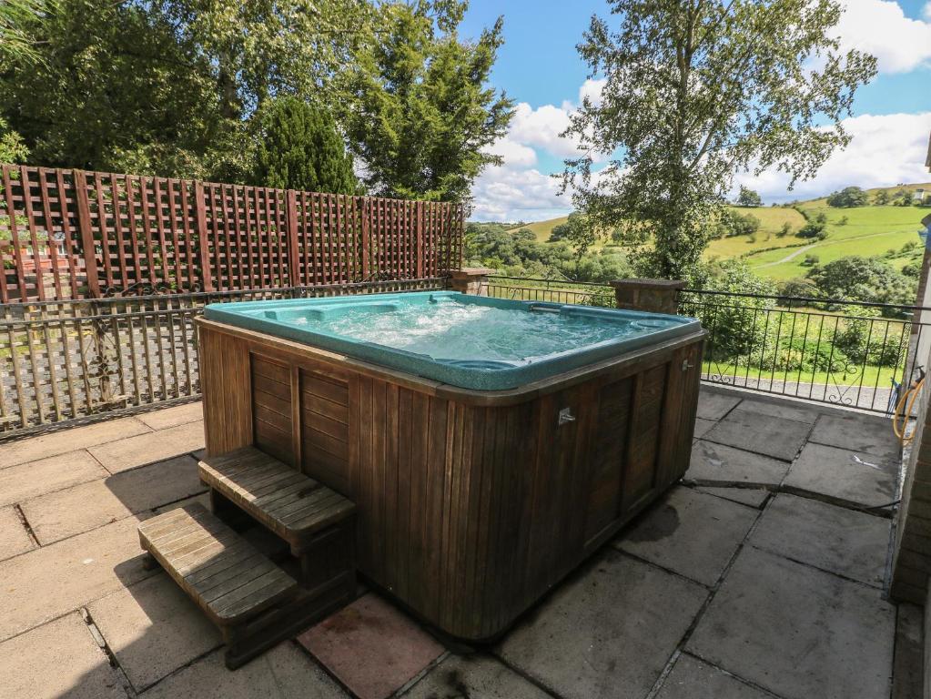a wooden hot tub with a bench next to a fence at Hillside Lodge in Llandrindod Wells