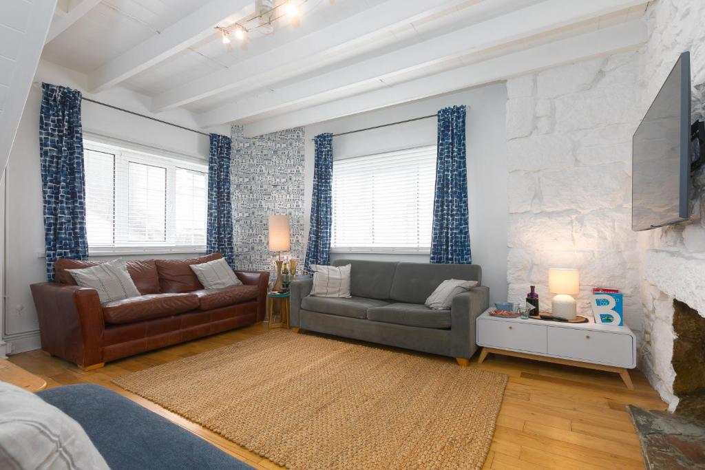 una sala de estar con 2 sofás y una pared de piedra. en Floyd's en St Ives