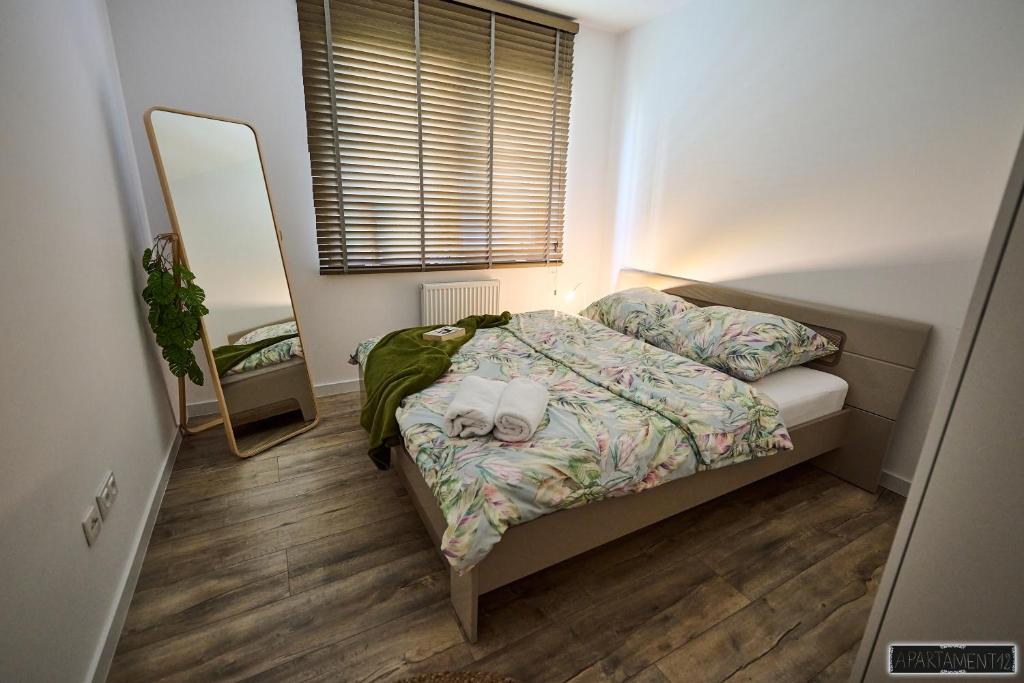 a small bedroom with a bed and a mirror at Apartament 12 in Chojnice