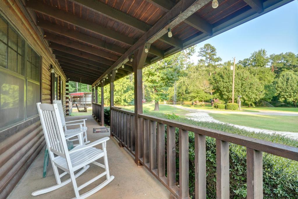 2 fauteuils à bascule installés sur la terrasse couverte d'une maison dans l'établissement Kilgore Gem Pet-Friendly Cabin with Duck Pond!, à Kilgore