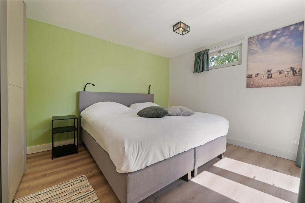 een slaapkamer met een bed met witte lakens en groene muren bij Vuurtorenveld 136 - Het Oude Nieuwland Ouddorp - NOT FOR COMPANIES in Ouddorp