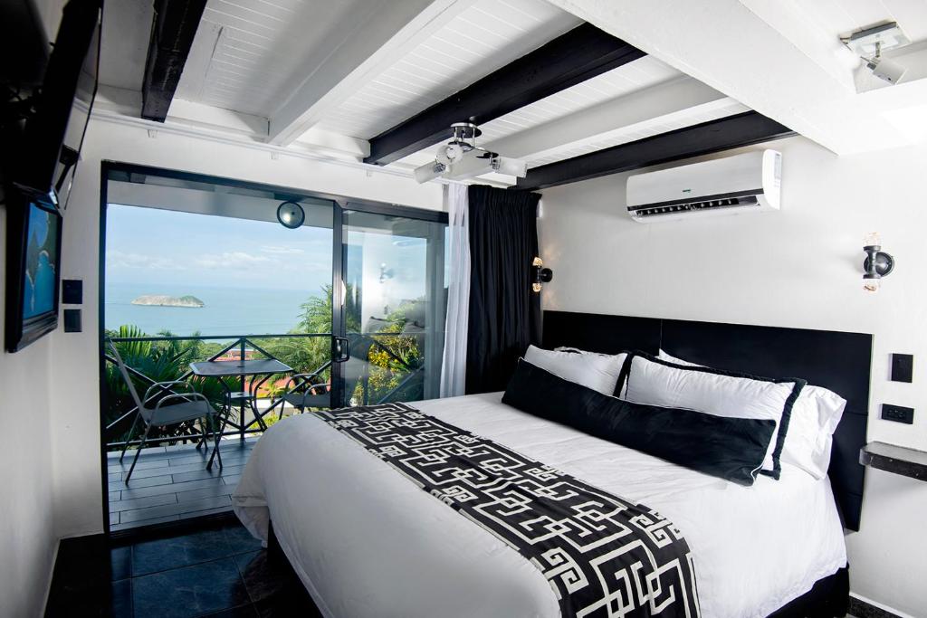 a bedroom with a bed and a view of the ocean at Villa Roca Boutique Resort & Suites - ADULT ONLY in Manuel Antonio