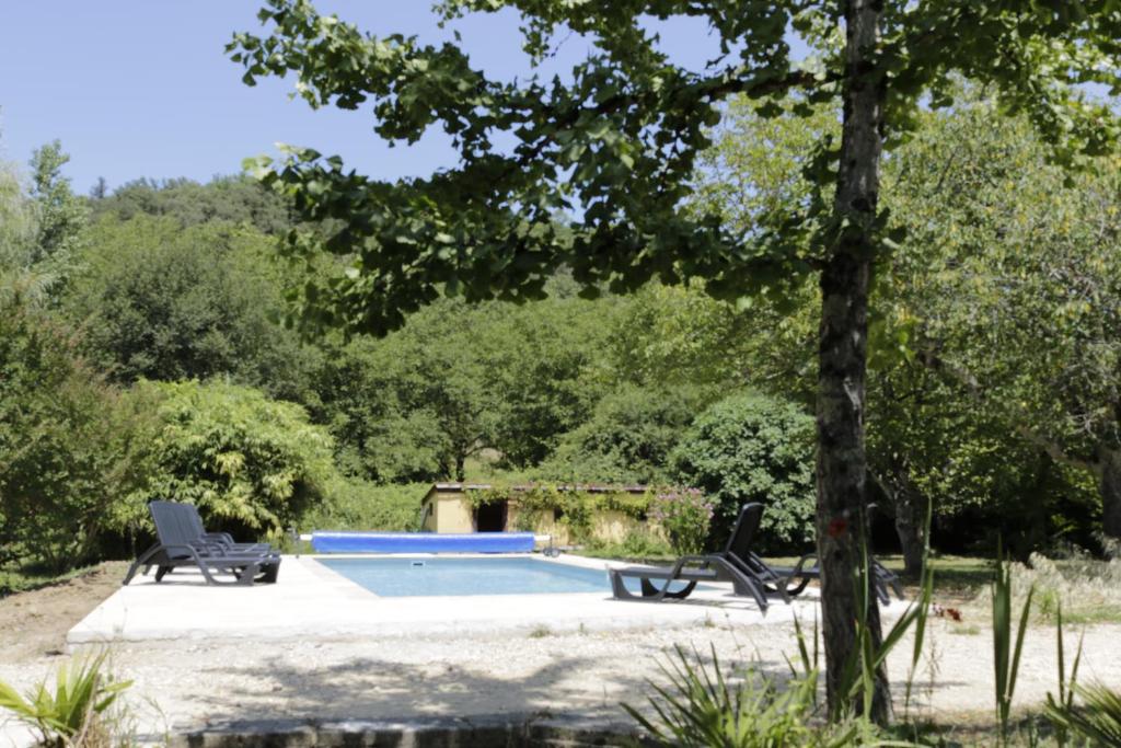 een zwembad met 2 stoelen en een boom bij Maison dans le bourg, 6-8 couchages avec piscine in Groléjac