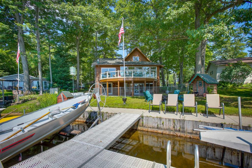 una casa con muelle y un barco en el agua en Lakefront Cadillac Retreat with Sauna and Boating! en Cadillac
