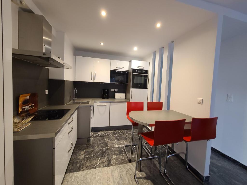 une cuisine avec une table et des chaises rouges dans l'établissement New Centre ville 3P clim, à Antibes