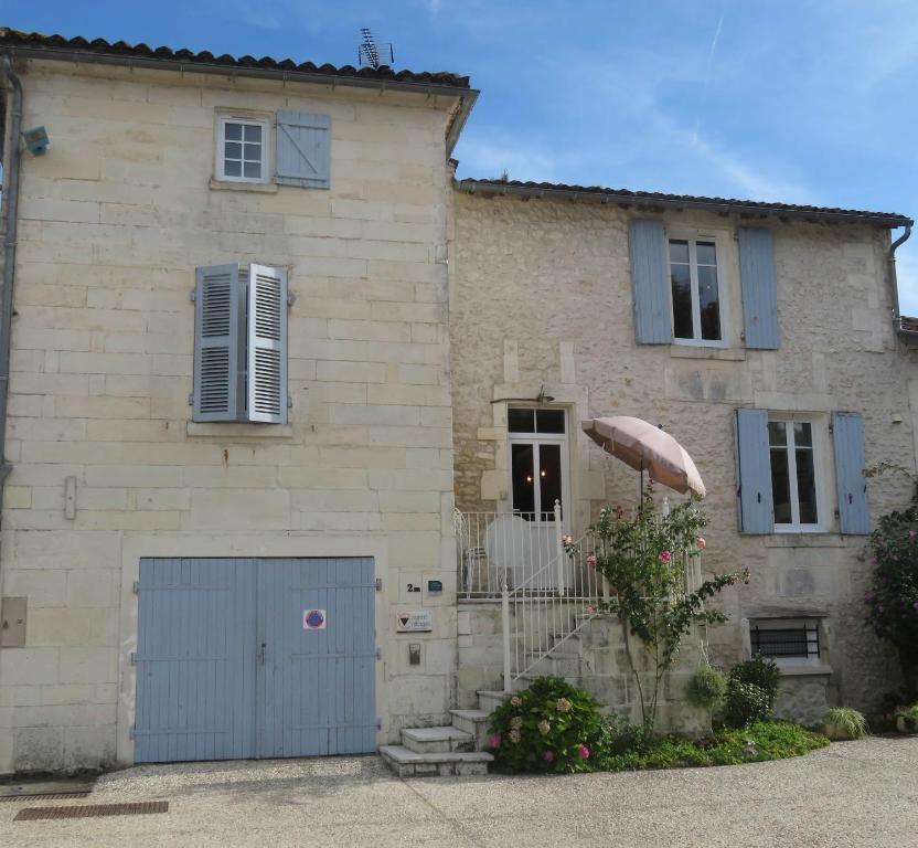 a large stone house with a blue garage at La Maison de Riviere in Bourg-Charente