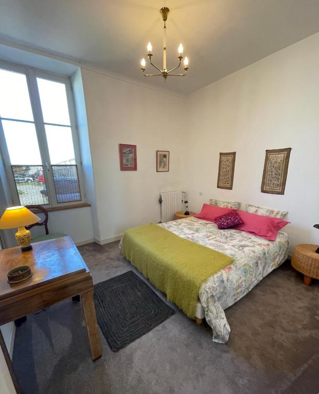 a bedroom with a bed with pink pillows and a table at Ferme de Maillezais in LʼHoumeau