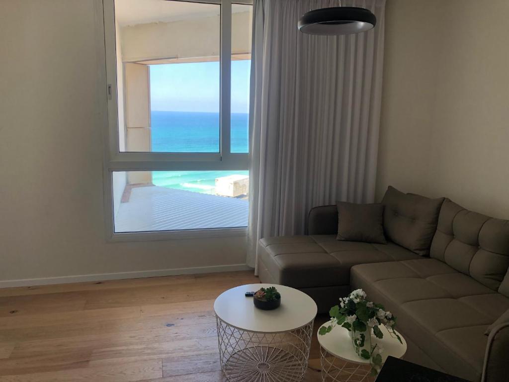 sala de estar con sofá y vistas al océano en תמר על הים en Bat Yam