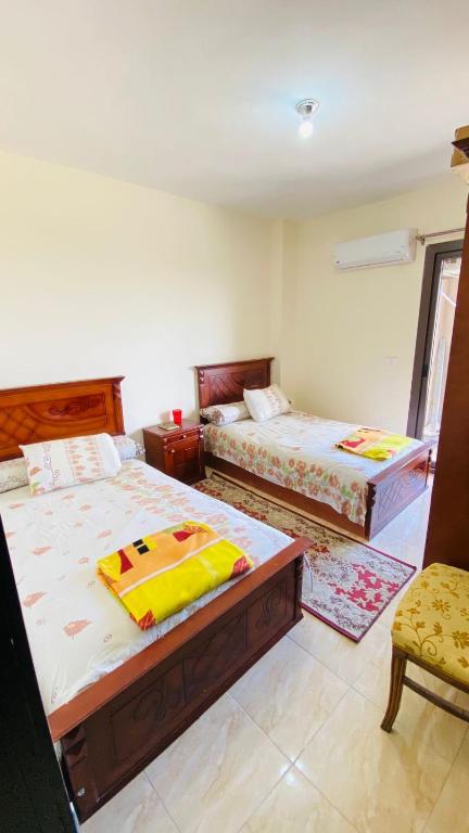 una camera con due letti e una sedia di جراند هيلز الساحل الشمالي Grand Hills North Coast شالية فندقي H047 عائلات فقط a Dawwār ‘Abd Allāh