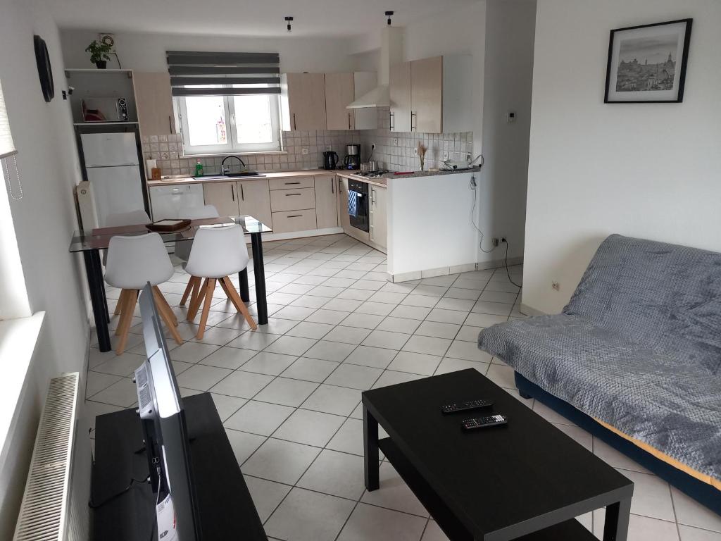ein Wohnzimmer mit einem Sofa und einer Küche in der Unterkunft Appartement 3 pièces avec balcon in Rhinau
