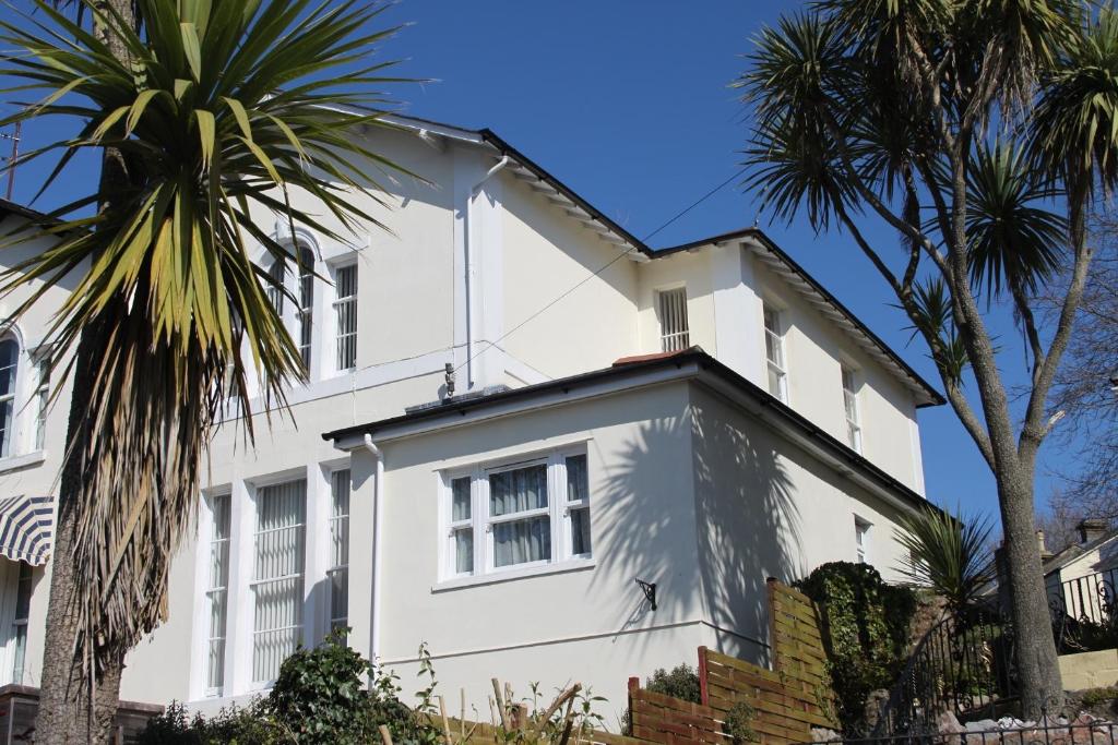 une maison blanche avec des palmiers devant elle dans l'établissement The Baytree, à Torquay