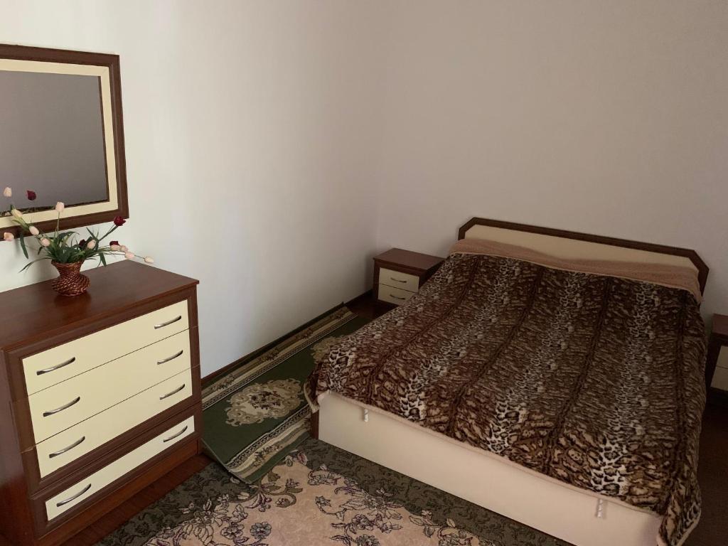 a bedroom with a bed and a dresser with a mirror at Коттедж Иссык-Куль солнышко VIP 2 in Chok-Tal