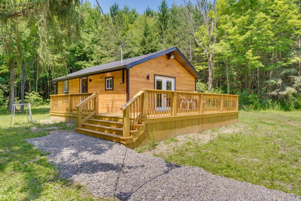 a cabin in the woods with a large deck at Cozy Ellicottville Cabin with Water Views - Near Ski in Ellicottville
