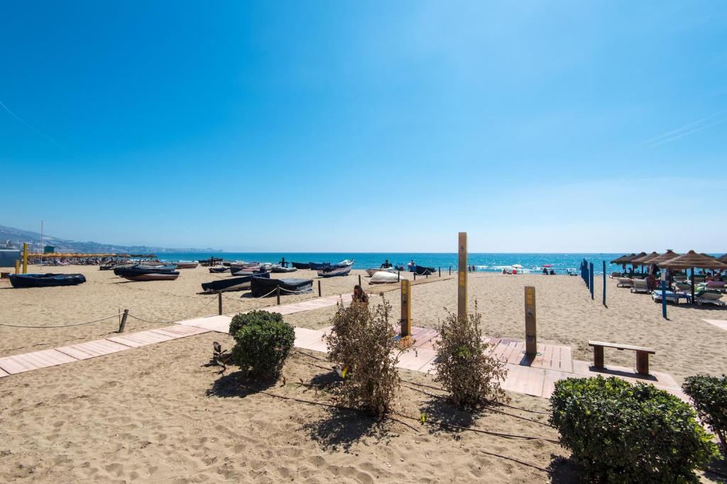 une plage de sable avec des arbres, des bancs et l'océan dans l'établissement BOLICHES CENTER APARTMENT next to the BEACH, PARKING, POOL & TERRACE, à Fuengirola
