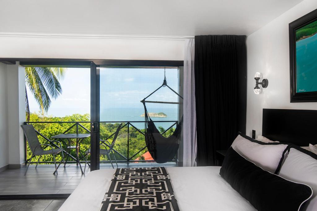 a bedroom with a bed and a view of the ocean at Villa Roca Boutique Resort & Suites - ADULT ONLY in Manuel Antonio