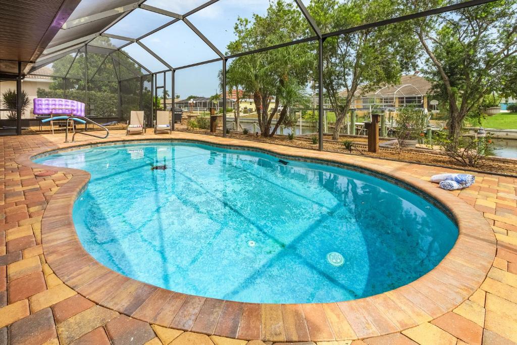 una gran piscina con techo de cristal en Gulf access, Heated Pool, outdoor kitchen, firepit & dock - Waterfront Paradise, en Cabo Coral